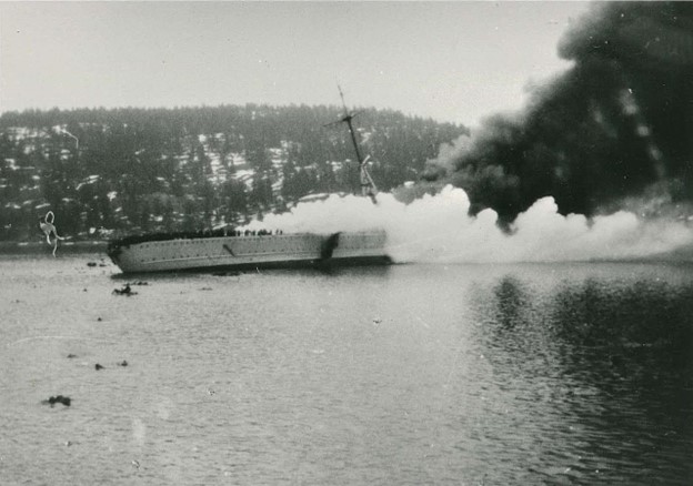 Black and white photograph of a Blücher warship on fire and beginning to list.